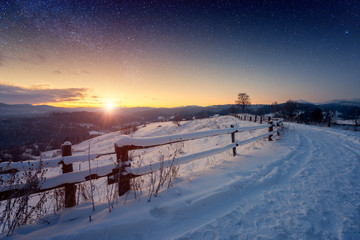 Beautiful winter fairytale landscape, stars and rising sun over the snowy mountain road