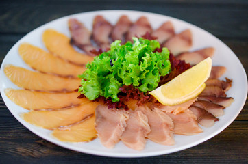 Thin and delicious red fish sliced ​​on a white dish with a slice of lemon