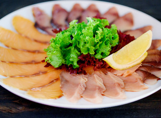 Thin and delicious red fish sliced ​​on a white dish with a slice of lemon