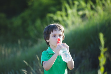 The child drinks water from a bottle