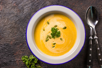 Seasonal autumn food - Spicy pumpkin soup with cream and pumpkin seeds.