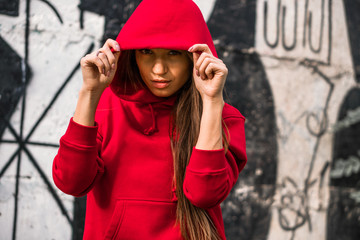 Adorable caucasian girl in costume for sport. Beautiful young fit fitness sport model in red sweetshotnear the painted wall.