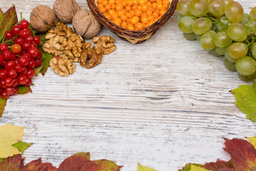 Vitamins of autumn. Viburnum, sea buckthorn, grapes, close-up on a light textured wooden background. Copy space