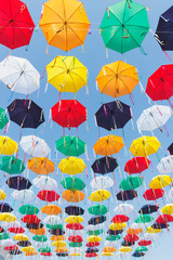 Fototapeta na wymiar Colored umbrellas hanging above the street, blue sky