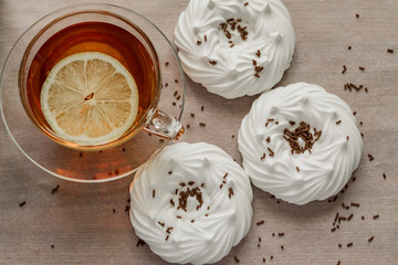 black tea with slice of lemon in transparent cup an air homemade meringues close up