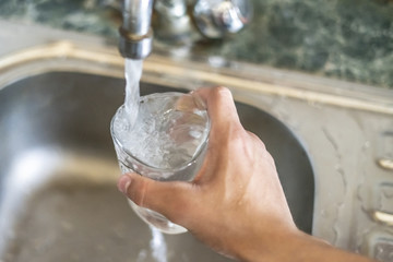 close up hand holding glass fill with water pour from tap d