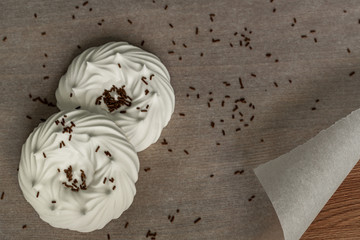 top view of homemade white air meringues and confectionery decorations on  on parchment paper.