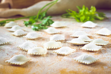 Fototapeta na wymiar traditional white uncooked ravioli on a cutting board with flour, handmade, on a wooden table. cooking process