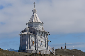 Fototapeta na wymiar Wooden church in Antarctica on Bellingshausen Russian Antarctic research station and helicopter