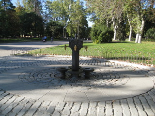 Fuente de hierro para beber con cubos de recogida de bronce y grifos dorados  rodeada de adoquines...