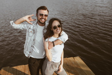 Happy couple on pier showing horns gesture
