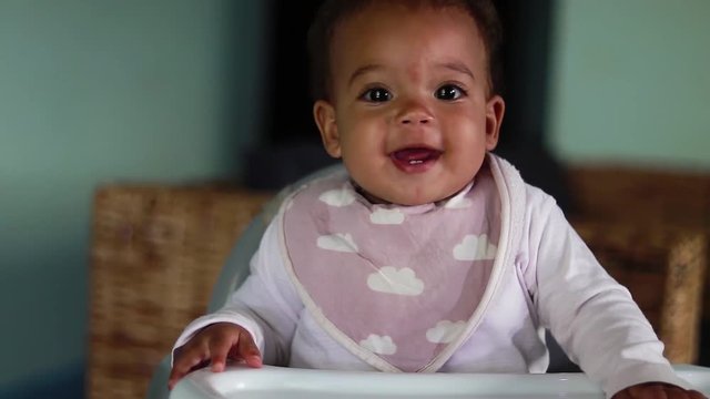 A baby very happy and joyful in a highchair.