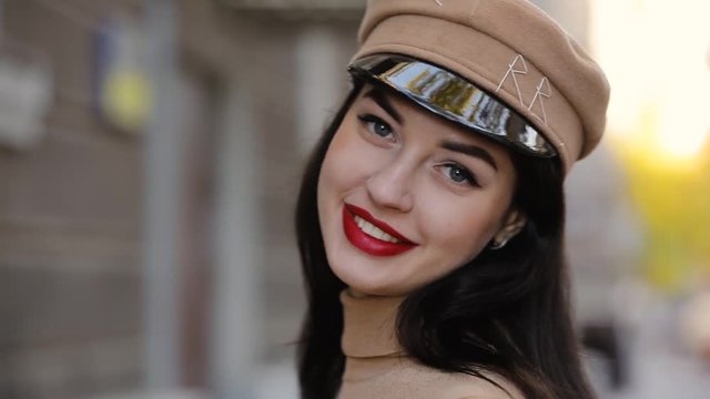 Glamorous model with red lips posing in hat with visor