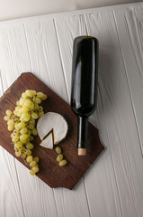 Bottles of wine on a white wooden background with grapes and Camembert cheese