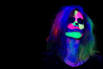 Woman with her face painted with neon make up with a skull design for halloween and santa muerte
