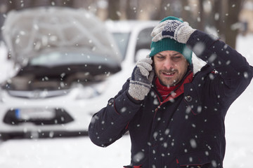Young man in snow, he is under stress because his broken down car.