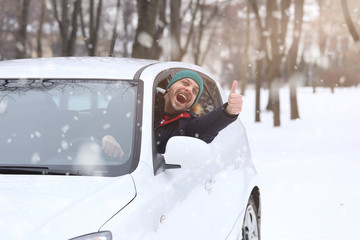 Portrait of car  driver with smile santa hat and thumb up through car window. On the road winter...