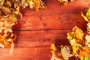 Obraz premium Autumn leaves and acorns on rustic wooden background. Fall background with copy space.