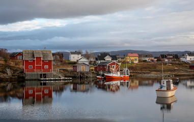 Fototapeta na wymiar Red fishing pier and fishing boats in Salhus strait in Brnnoy municipality, Northern Norway