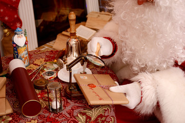 Santa Claus sealing a letter, looking through magnifier glass