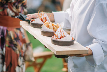 Catering service. Waiter carrying a tray of appetizers. Outdoor party with finger food, mini...
