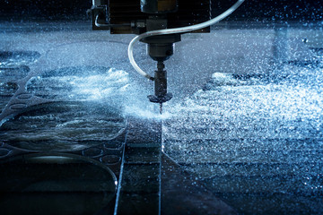 Water jet industrial machine cutting steel plate. Computer controlled metalworking machine using high pressure water jet to cut metal. - obrazy, fototapety, plakaty