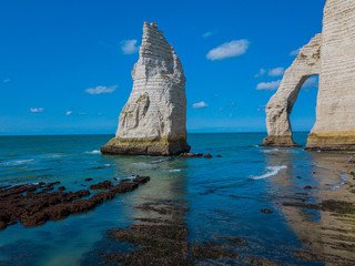 Fototapeta na wymiar Chalk cliffs of Etretat with the natural arch Porte d'Aval and the stone needle called L'Aiguille