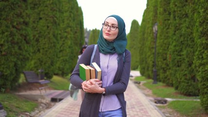Arab student in hijab with books goes to the park to study