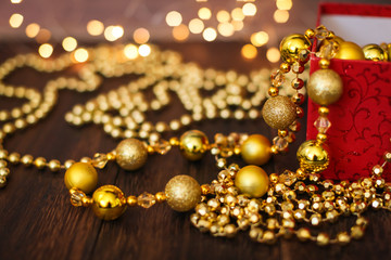 Close up golden christmas decoration balls from red gift box on dark wooden background and bokeh garland