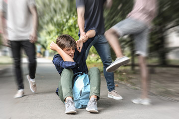 Aggressive teenagers bullying boy outdoors, view with motion blur effect - obrazy, fototapety, plakaty