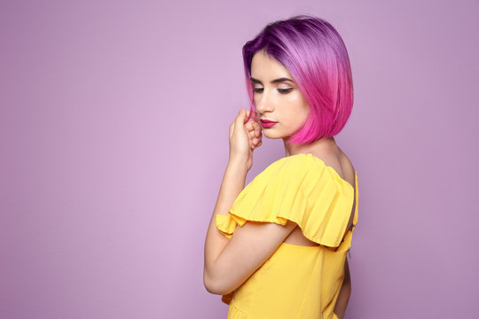 Young woman with trendy haircut against color background