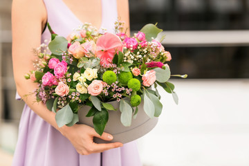 Woman holding gift box with beautiful flowers outdoors