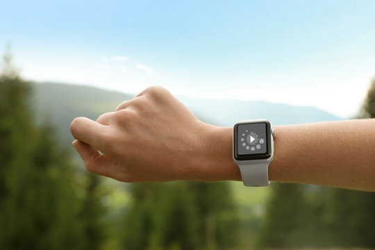 Woman checking smart watch with blank screen in wilderness, closeup