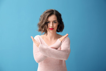 Portrait of beautiful woman showing STOP gesture on color background