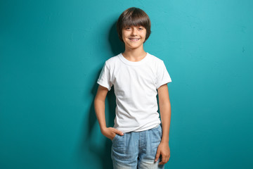 Smiling little boy in t-shirt on color background