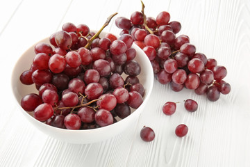 Bowl with sweet grapes on white wooden table