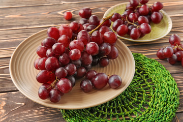 Plates with ripe grapes on wooden table