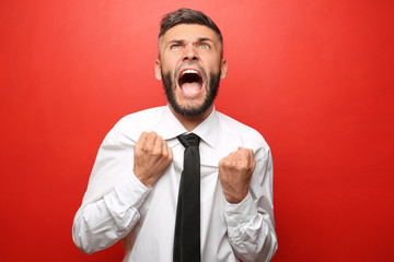 Portrait of aggressive businessman on color background