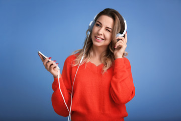 Portrait of beautiful young woman listening to music on color background