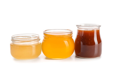 Glass jars with tasty honey on white background