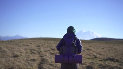 Beautiful muslim woman traveler with backpack and glasses looking at the camera and going to the mountains