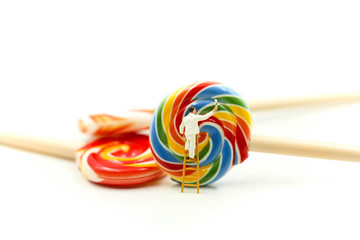Miniature people : worker painting with colorful candy lollipop.