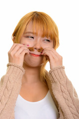 Young Asian woman smelling her hair while looking away