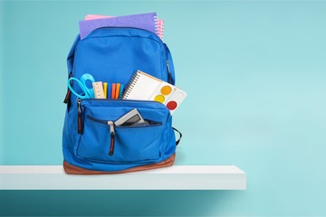 Colorful school supplies in backpack on wooden