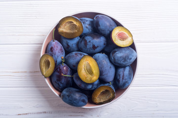 Fresh plums in bowl on wooden table