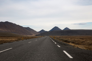 Long Empty Road in Iceland with Mountains and Hills in background