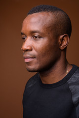 Studio shot of young African man against brown background