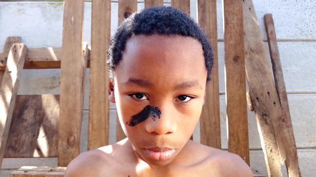 A child soldier puts on his war paint and prepares for battle.