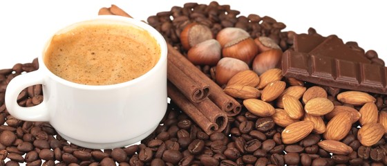 Cup of hot coffee with beans and cinnamon sticks on white