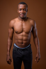 Fototapeta na wymiar Young shirtless African man against brown background